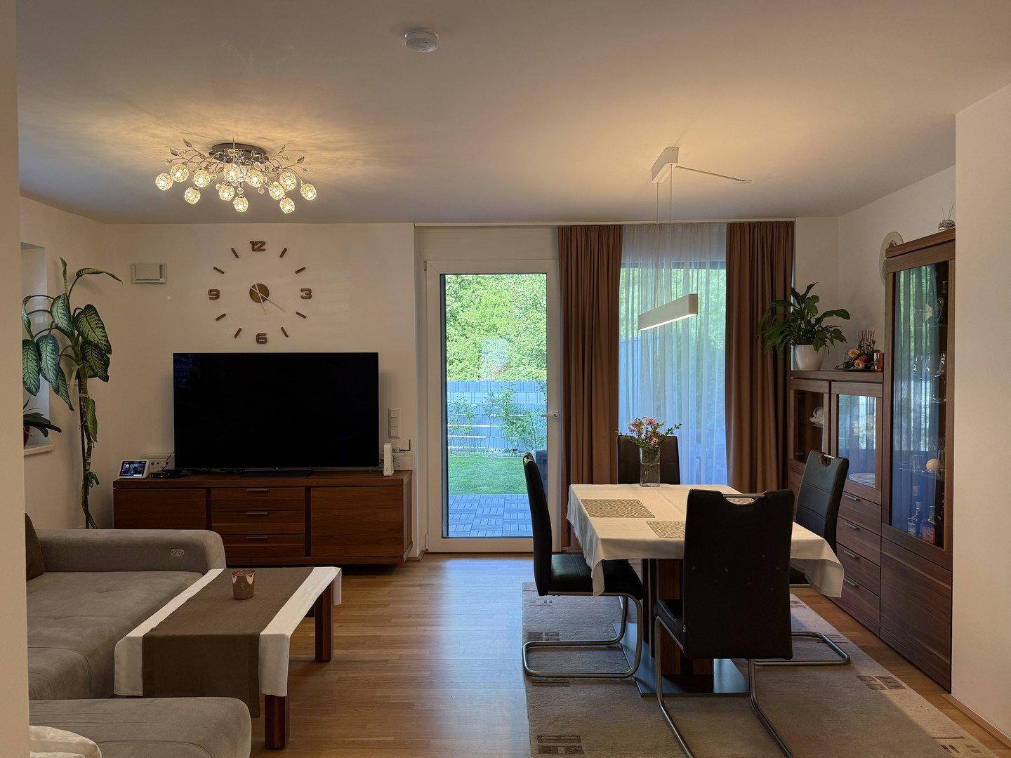 Heller Wohn- und Essbereich mit Holzboden, Zugang zum Garten und moderner Einrichtung.