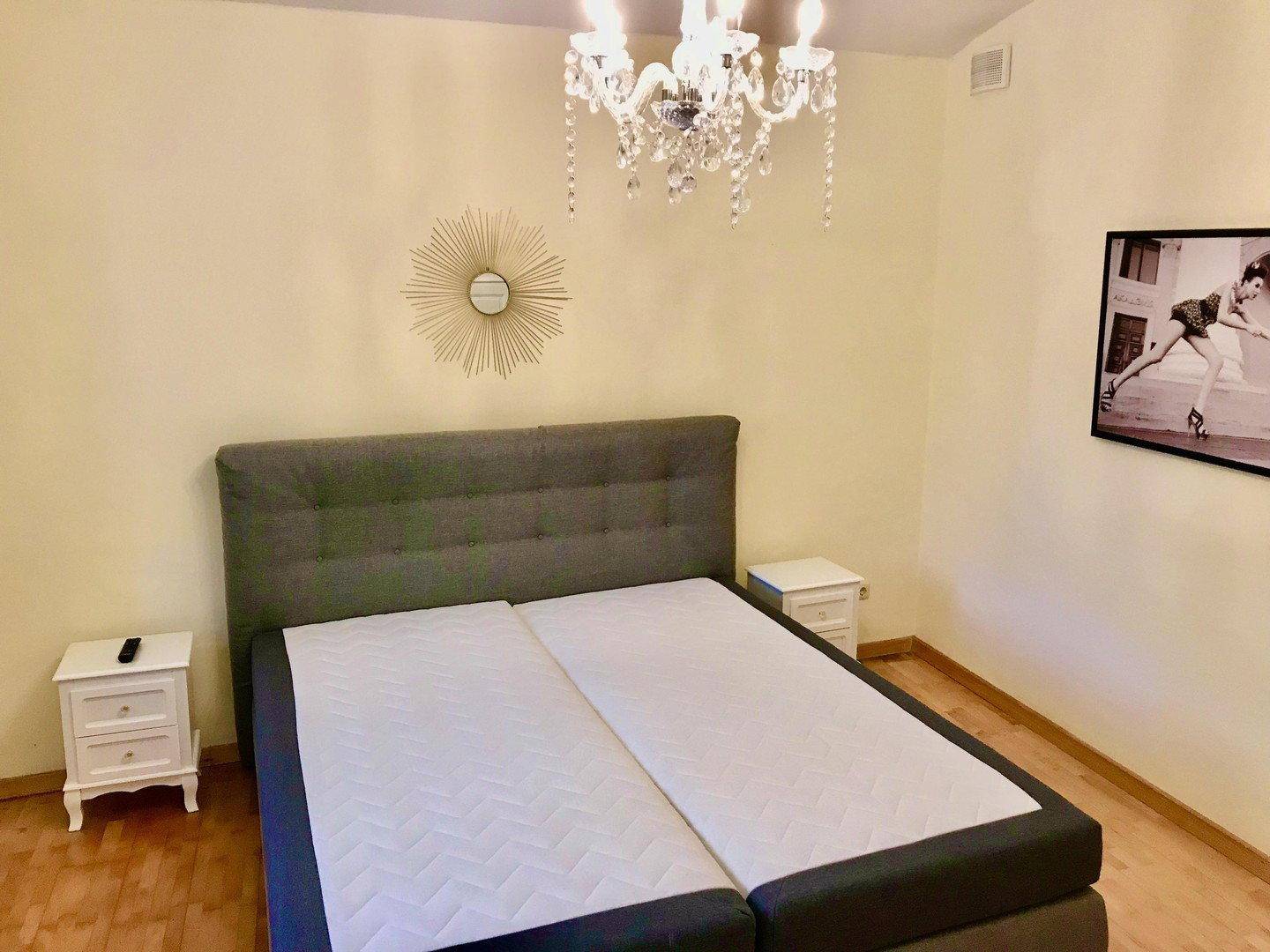 Schlafzimmer mit Doppelbett, Nachttischen und einem eleganten Kronleuchter.