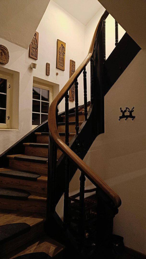 Elegante Holztreppe mit kunstvollem Geländer und dekorativen Wandelementen.