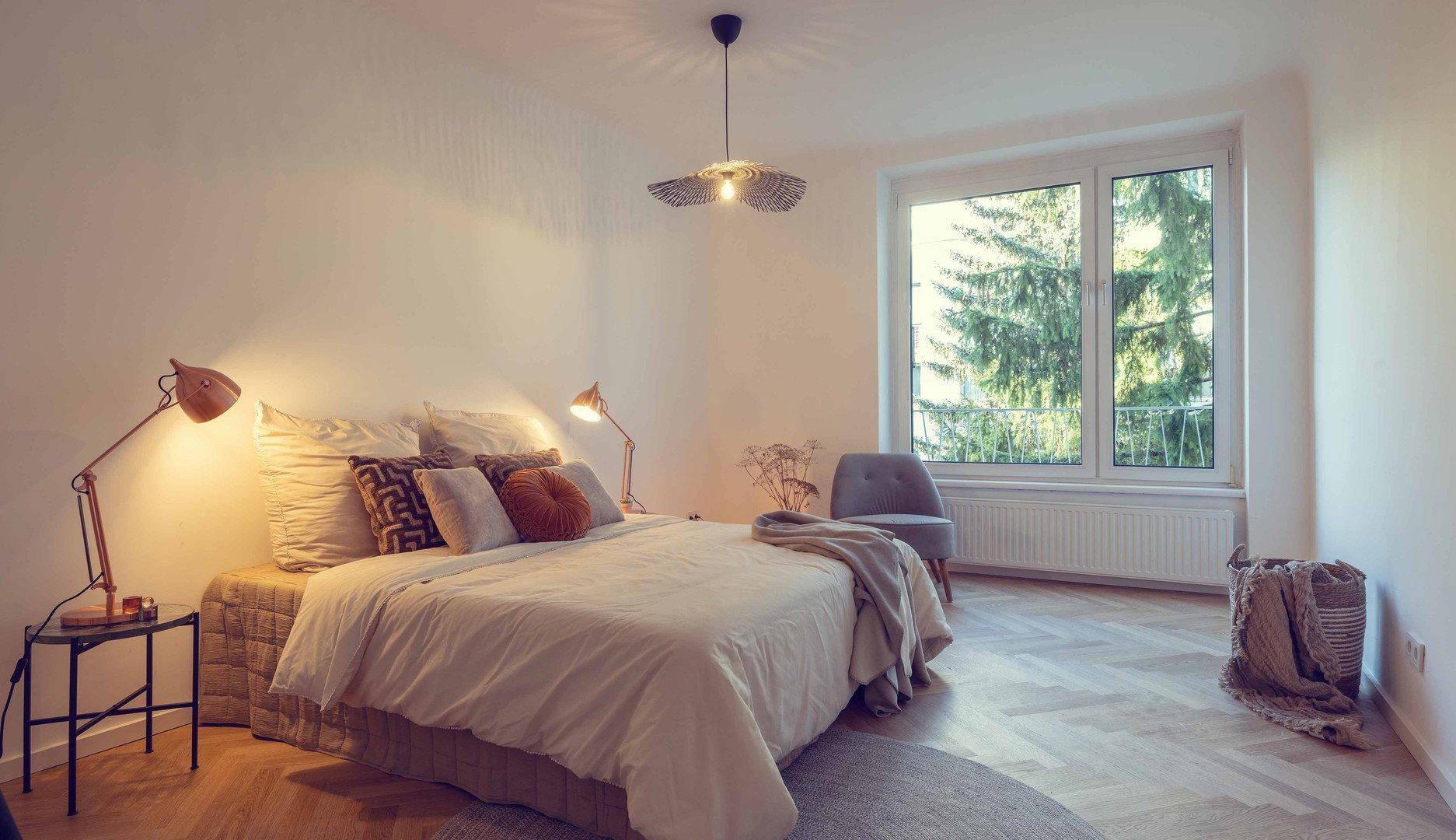 Helles Schlafzimmer mit großem Bett, Nachttischen und Fenster mit Blick ins Grüne.