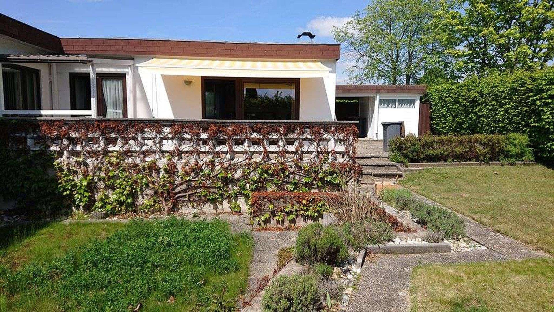 Großer Garten mit Terrasse, Markise und üppiger Bepflanzung.