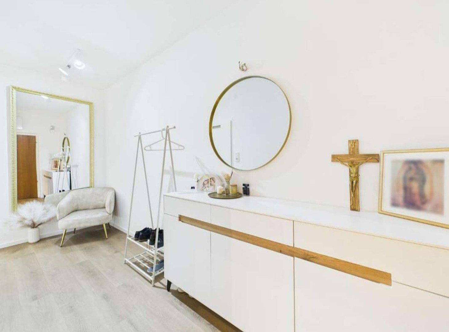 Heller Flur mit modernem Sideboard, großem Spiegel und dekorativen Elementen.