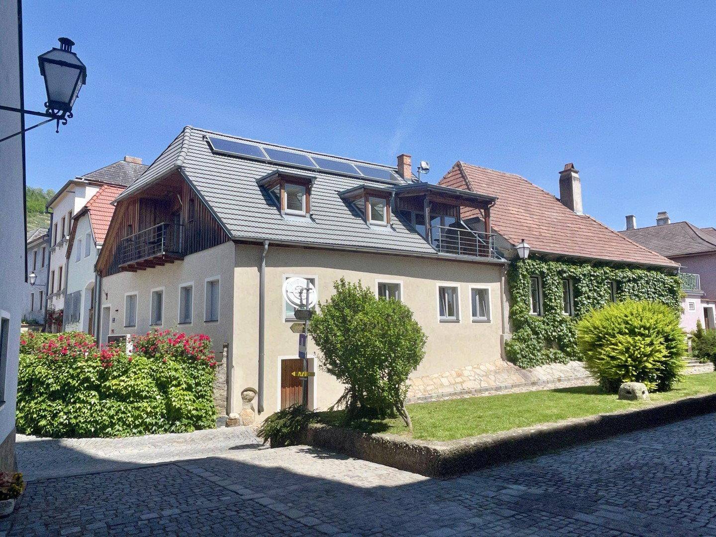 Attraktives Gebäude mit Solarpaneelen und begrünten Fassaden in einer sonnigen Umgebung.