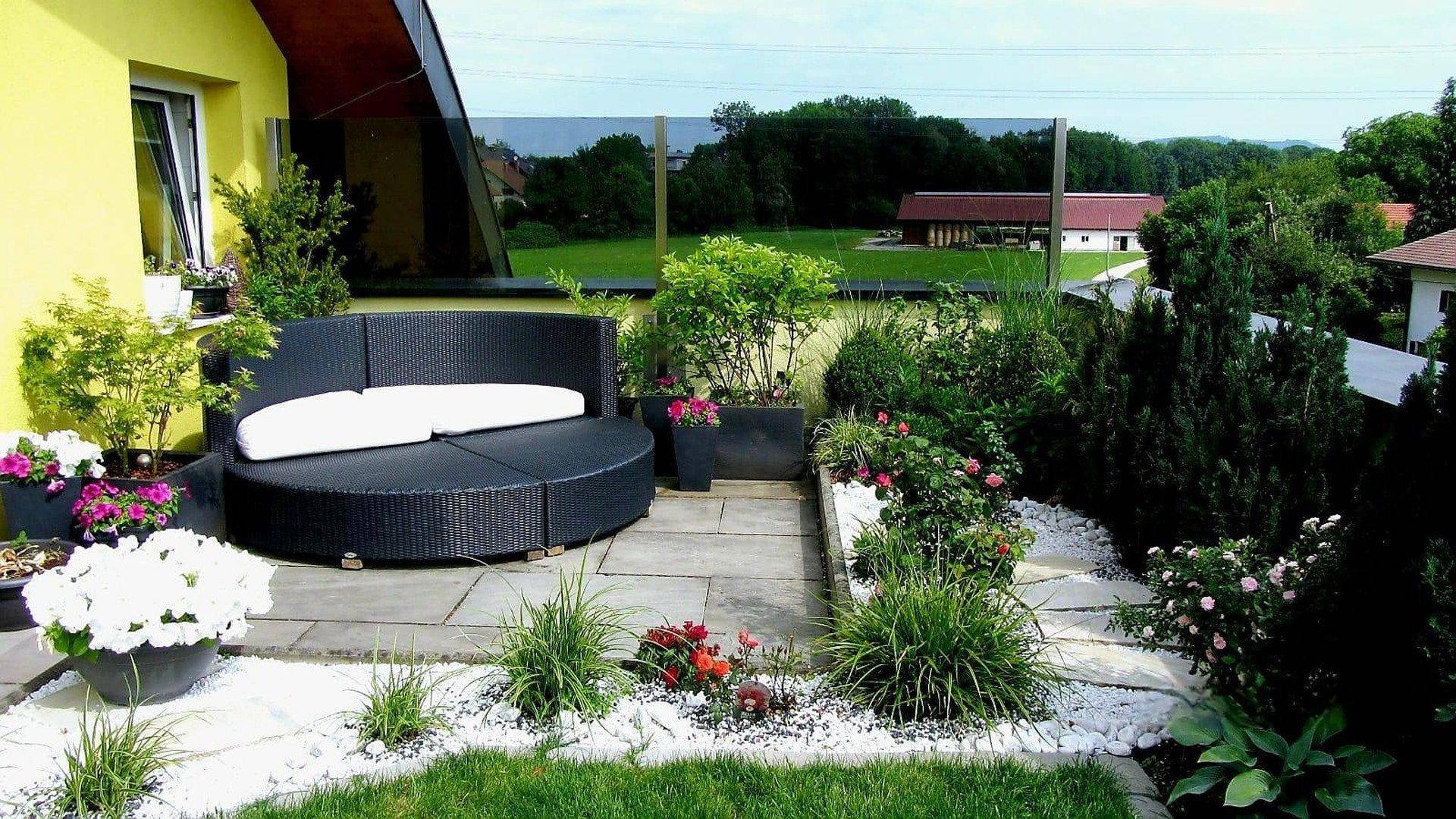 Gepflegter Gartenbereich mit Liegefläche, Zierpflanzen und Kieswegen.