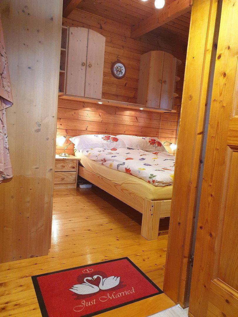 Gemütliches Schlafzimmer mit Holzboden, Holzwänden und einem bequemen Doppelbett.