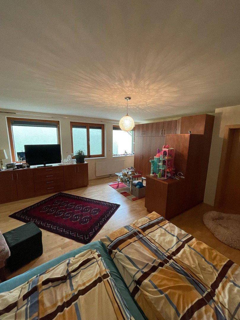 Helles Schlafzimmer mit Holzboden, großen Fenstern und einem gemütlichen Bett im Vordergrund.
