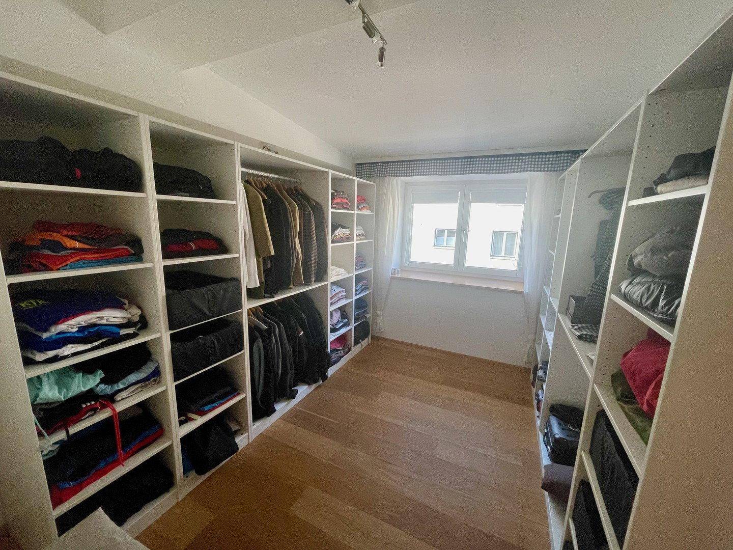Geräumiger begehbarer Kleiderschrank mit offenen Regalen und viel Stauraum.