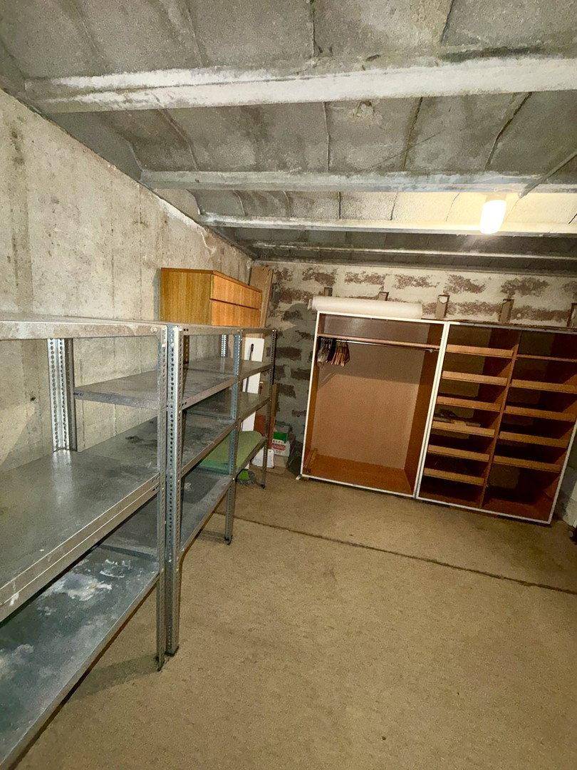 Geräumiger Kellerraum mit Betonwänden und Metallregalen, ideal für Lagerzwecke.