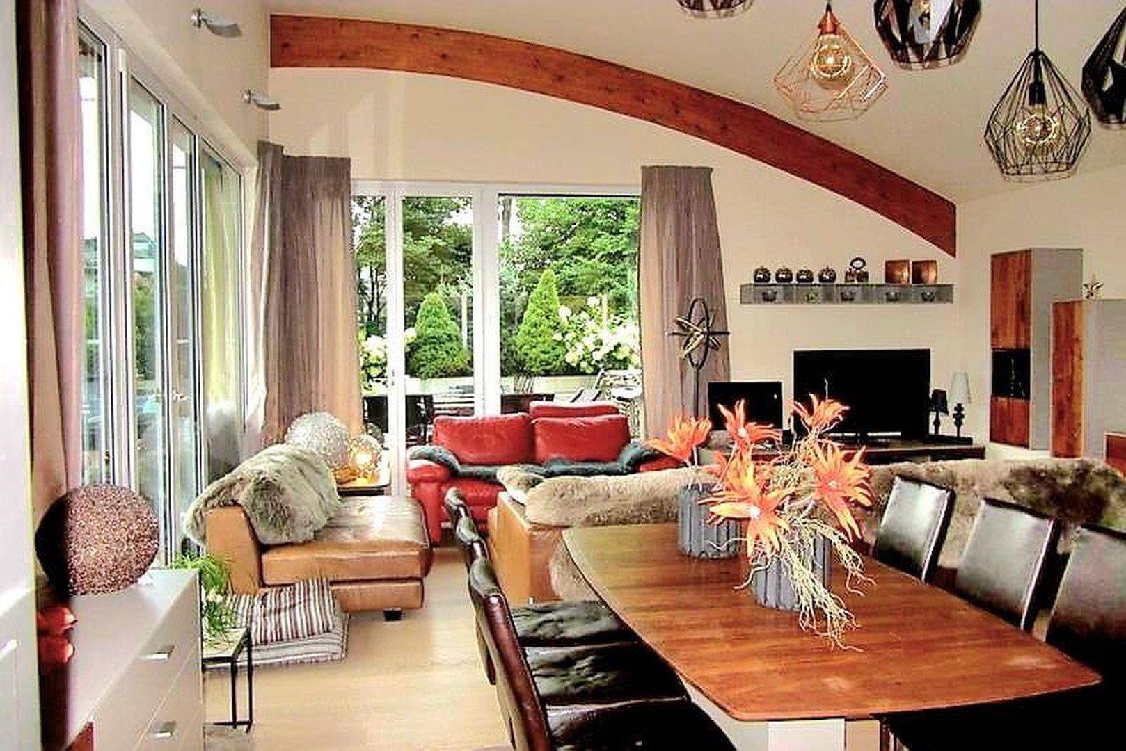 Geräumiger Wohn- und Essbereich mit Holzboden, großen Fenstern und Zugang zur Terrasse.