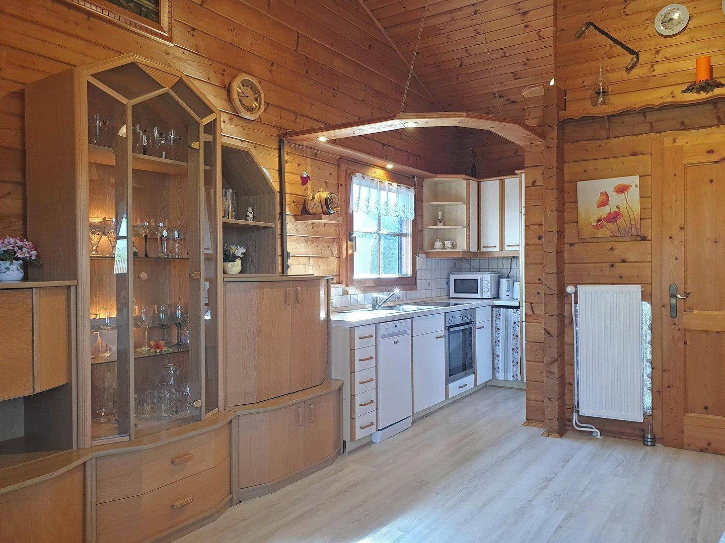 Kleine Einbauküche mit weißen Schränken, integriert in den offenen Wohnbereich des Holzhauses.