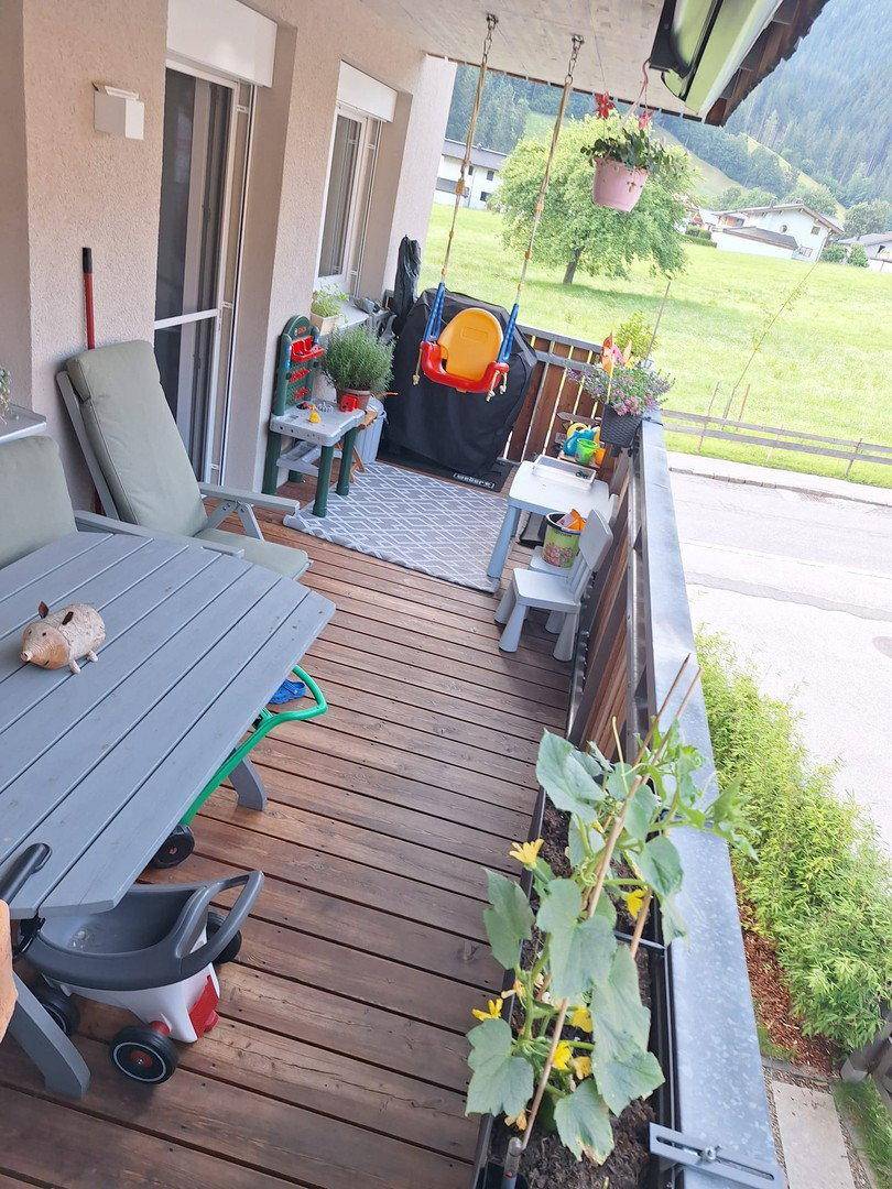 Geräumiger Balkon mit Holzboden, Kinderspielzeug und Bergblick.