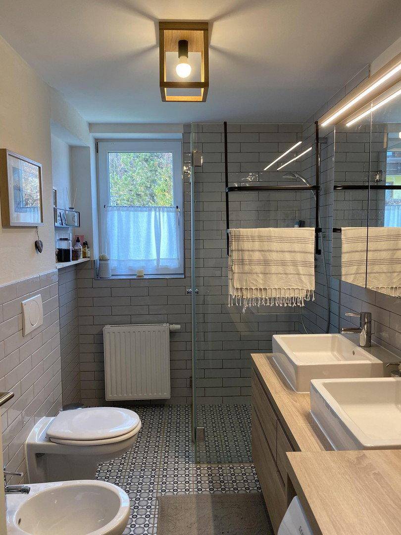 Modernes Badezimmer mit Doppelwaschbecken, Dusche und Fenster.