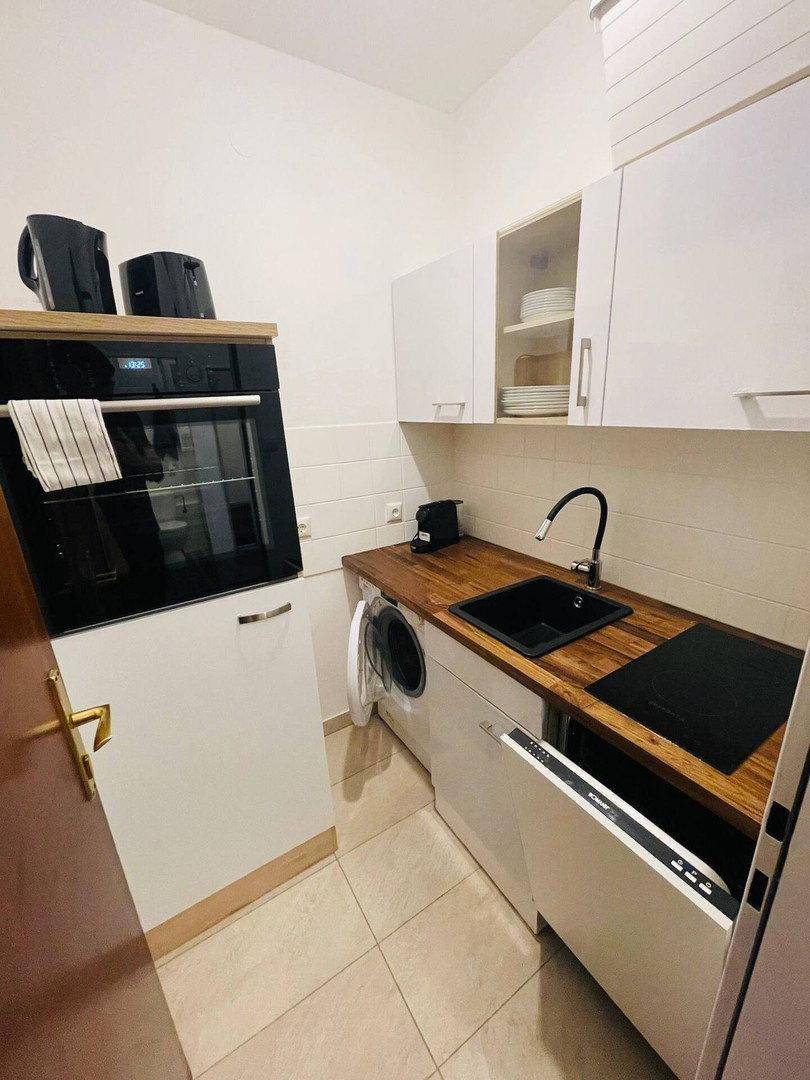 Funktionale Küchenzeile mit Backofen, Spüle, Kochfeld und integrierten Haushaltsgeräten.