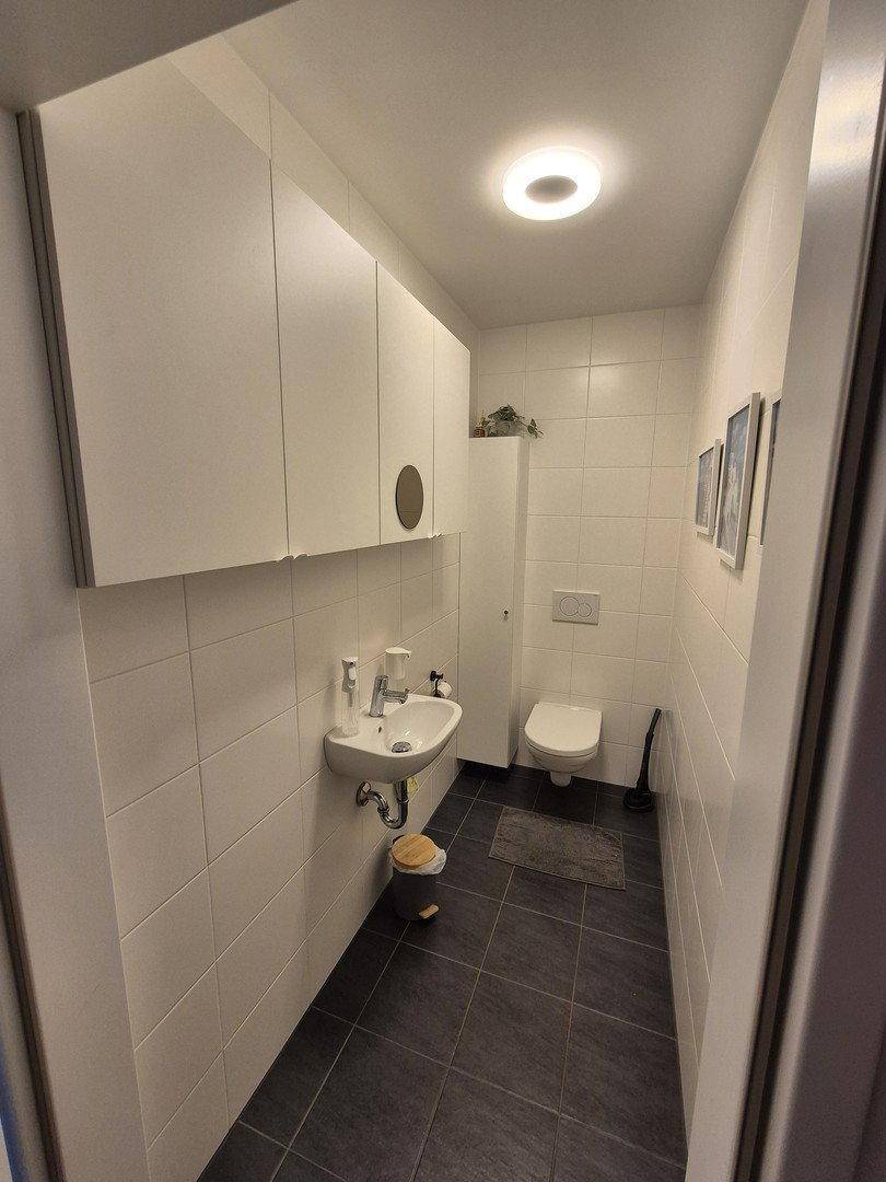 Kleines Gäste-WC mit wandhängendem WC, Waschbecken und weißen Fliesen.