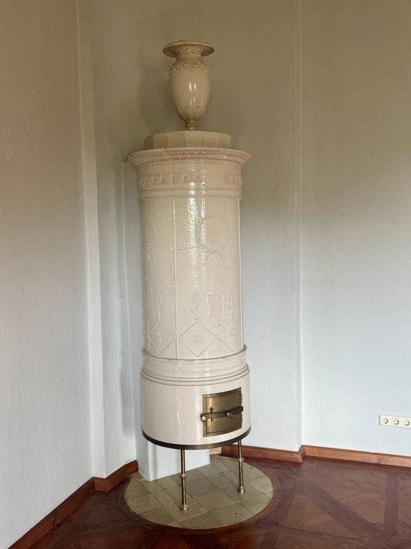 Detailansicht eines eleganten, traditionellen weißen Kachelofens mit Verzierungen.