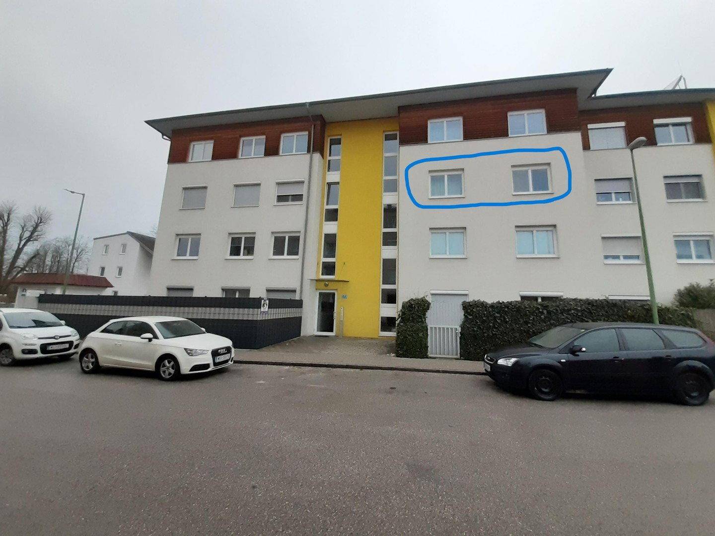 Ansicht der modernen Wohnanlage von der Straße mit parkenden Autos.