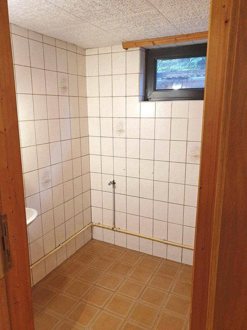 Kellerraum mit Fliesenboden, gefliesten Wänden und kleinem Fenster für Belüftung.