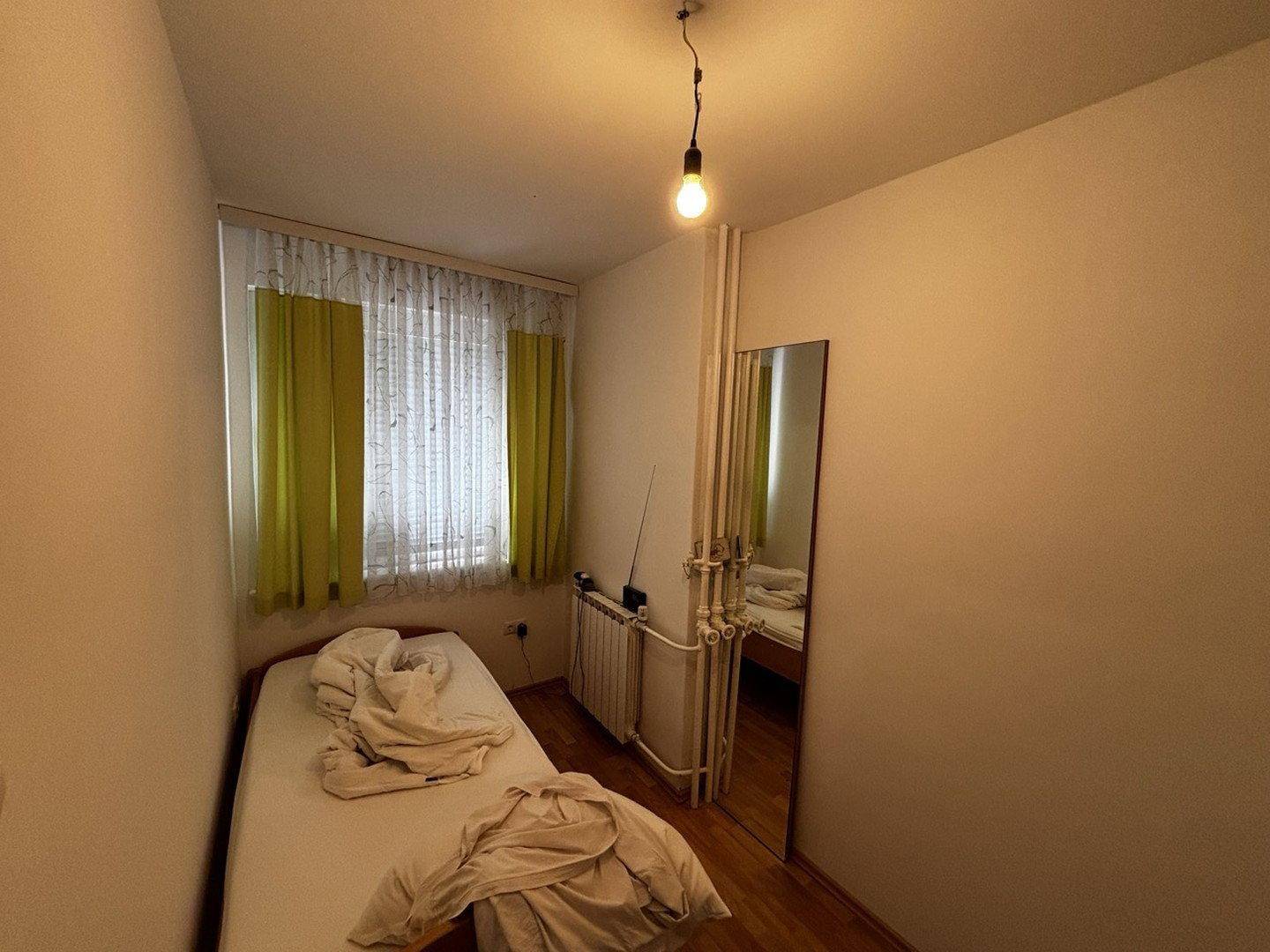 Kleines Schlafzimmer mit Einzelbett, Fenster und Heizkörper.