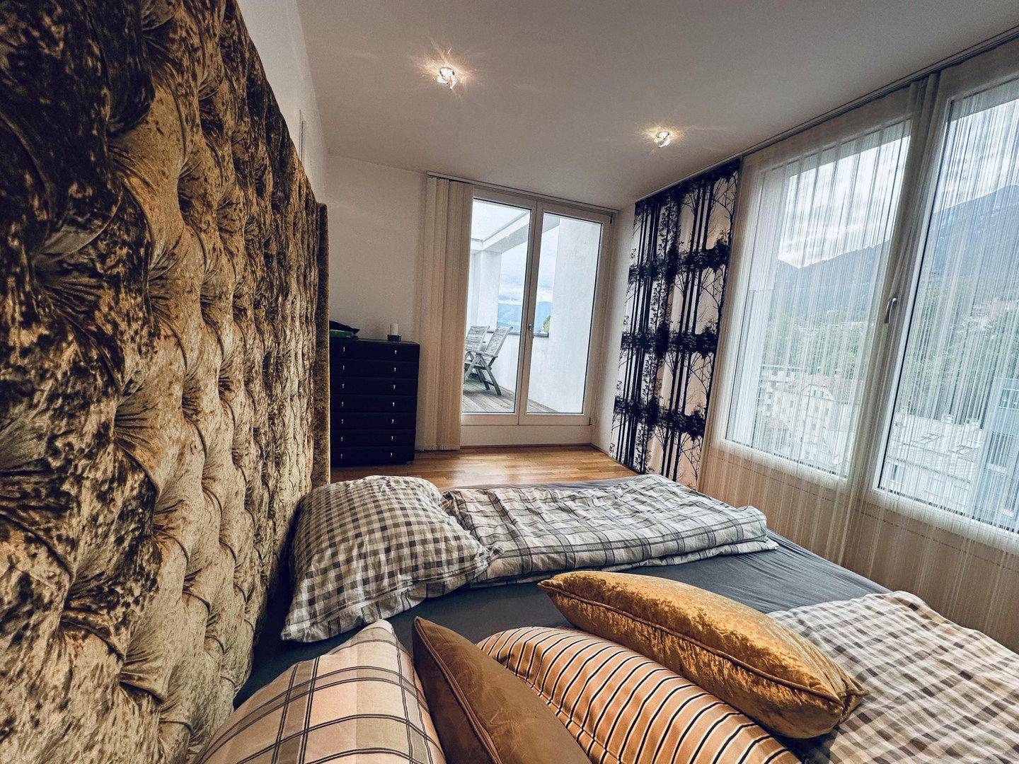 Gemütliches Schlafzimmer mit großem Bett, Holzboden und Blick auf die Berge von der Terrasse.
