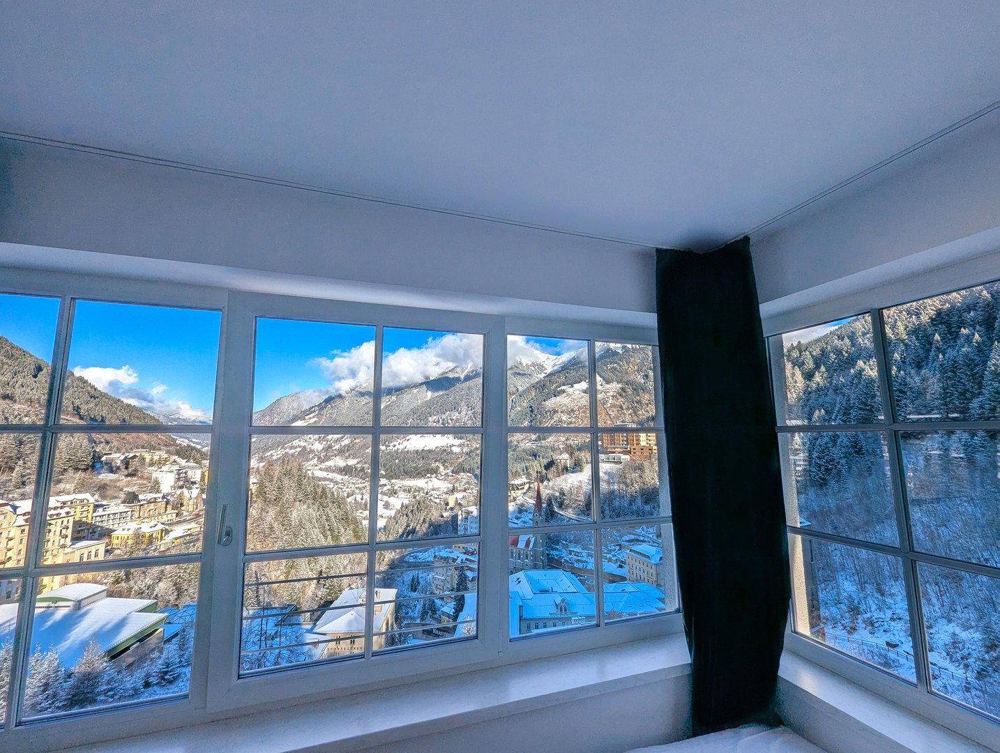 Schlafzimmerfenster mit weitem Blick auf die verschneite Berglandschaft und das winterliche Tal.