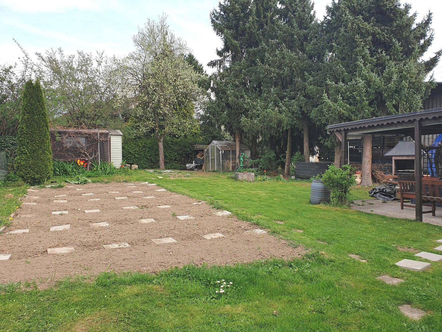 Großer Gartenbereich mit Rasenfläche, vorbereitetem Gemüsebeet und Gartenhäuschen.