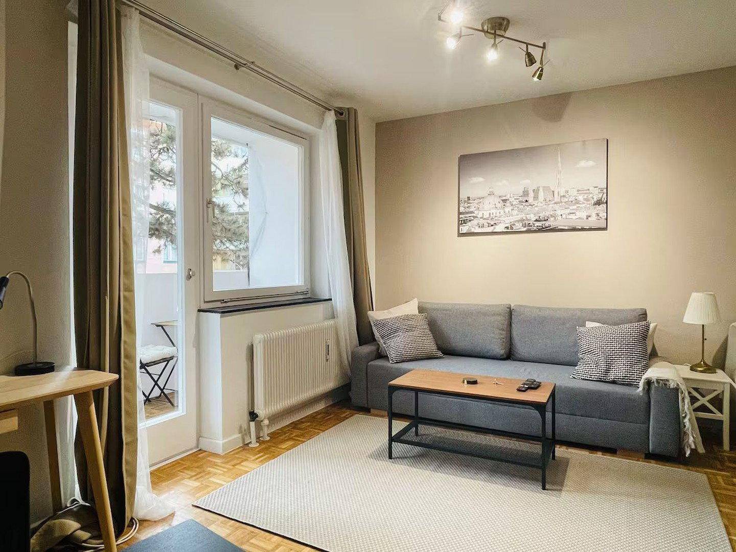 Gemütlicher Wohnbereich mit Sofa, Couchtisch und großem Fenster mit Balkonzugang.