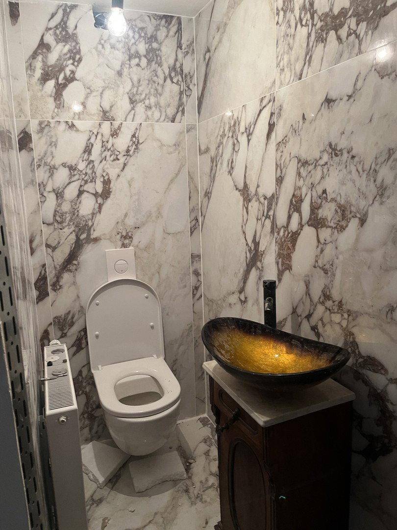 Modernes Gäste-WC mit Marmorfliesen, Wand-WC und auffälligem Aufsatzwaschbecken.