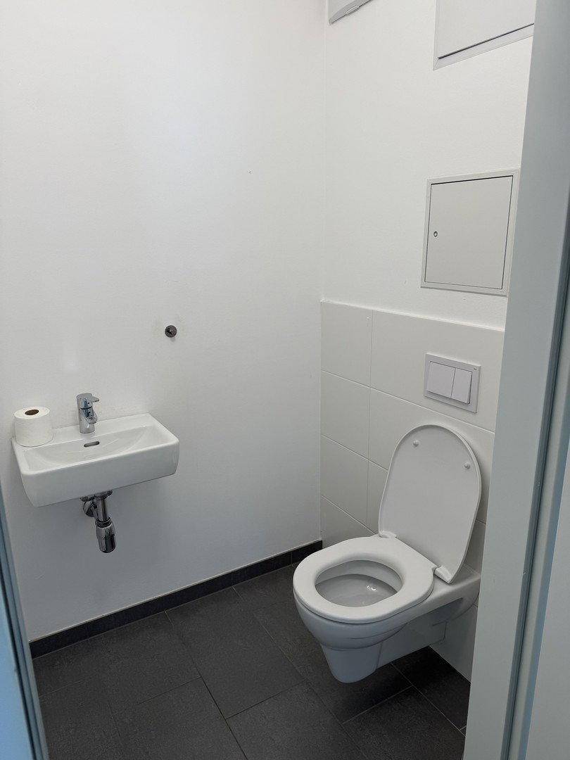 Separates Gäste-WC mit wandhängender Toilette und kleinem Handwaschbecken.