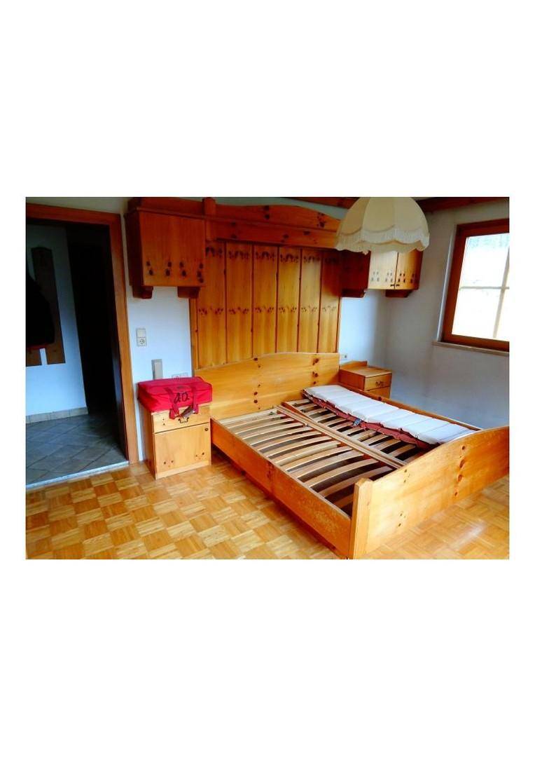 Schlafzimmer mit traditionellem Holzbett, Holzboden und Einbauschränken, bietet eine gemütliche Atmosphäre.