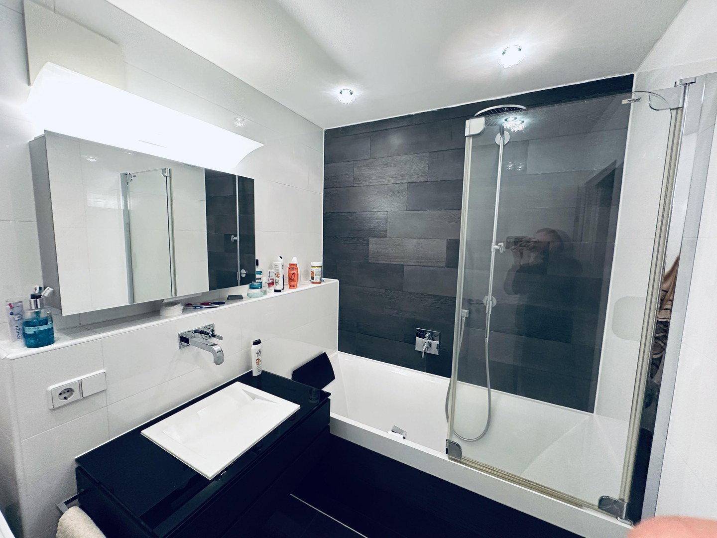 Modernes Badezimmer mit Badewanne, Duschabtrennung und Spiegelschrank über dem Waschbecken.