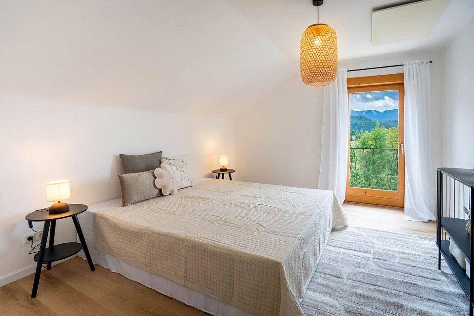 Gemütliches Schlafzimmer mit Doppelbett, Nachttischen und Zugang zu einem französischen Balkon.