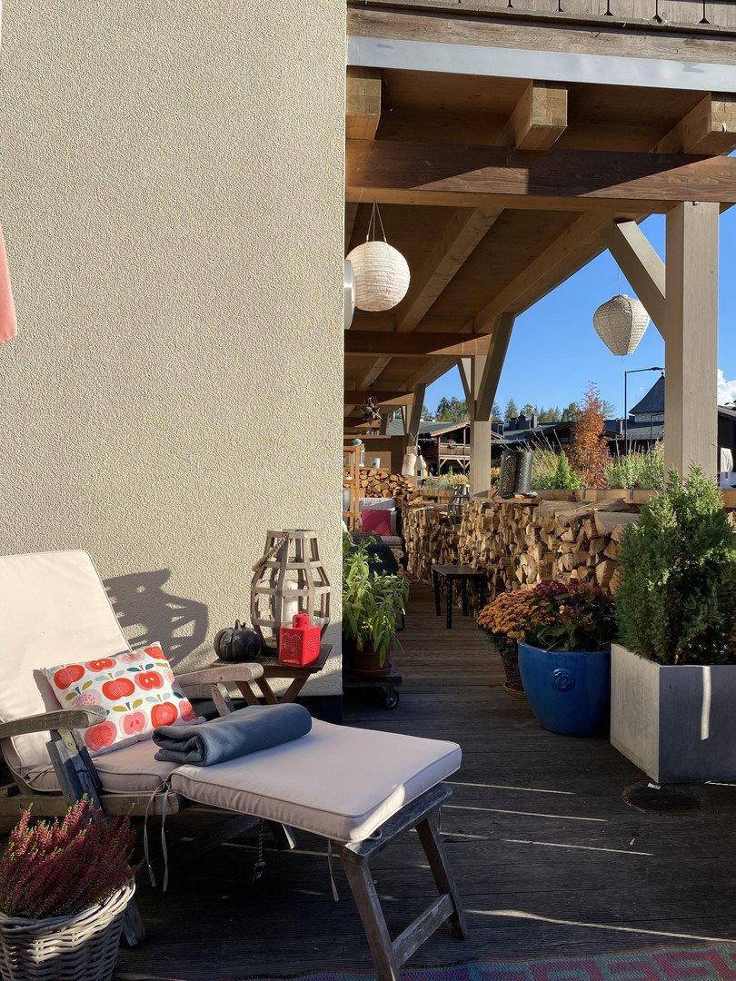 Gemütlicher überdachter Balkon mit Pflanzen, Liegestuhl und Blick ins Grüne.