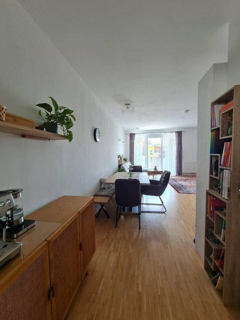 Langer Wohn-Essbereich mit Parkettboden, Esstisch und Blick zum Balkon.