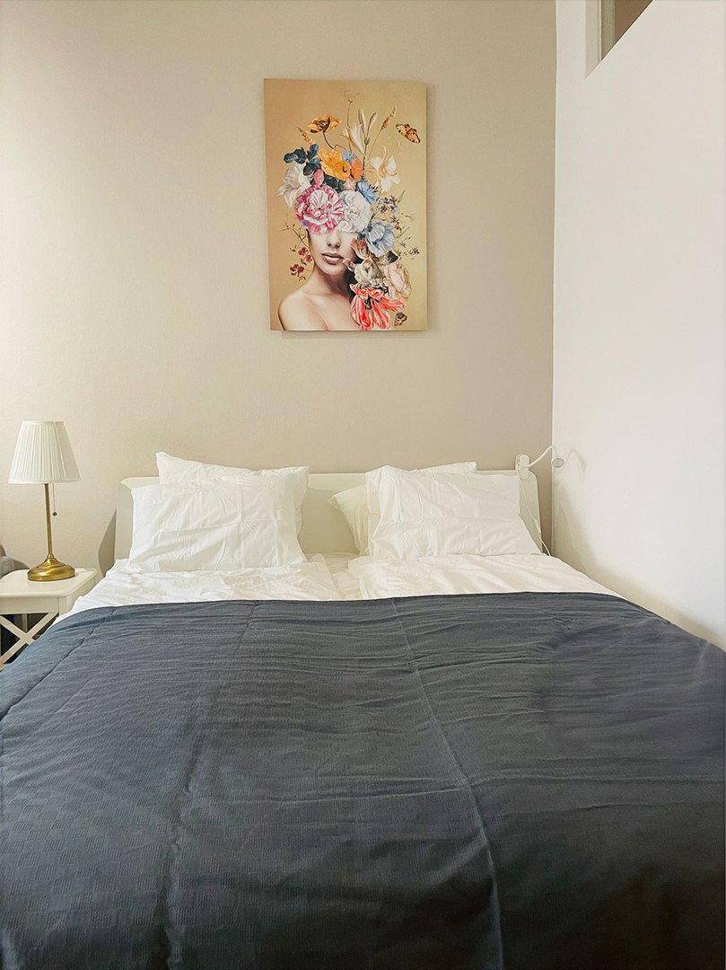 Nahaufnahme eines komfortablen Doppelbettes mit weißer Bettwäsche und floralem Wandbild.