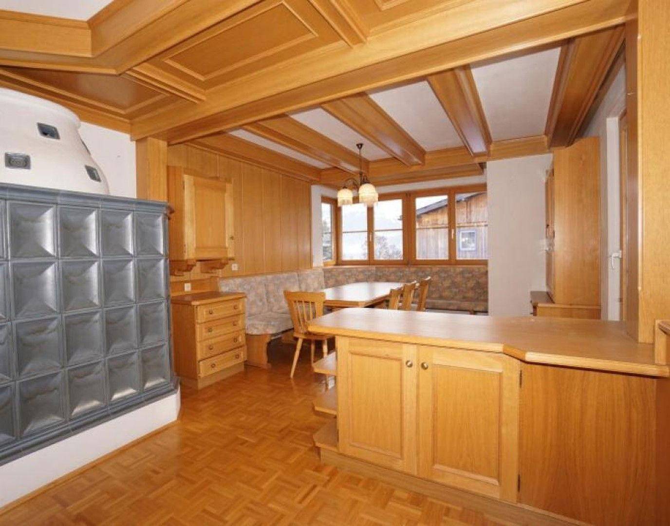Gemütlicher Essbereich im alpinen Stil mit Holztisch, Eckbank und Blick auf den Kachelofen.
