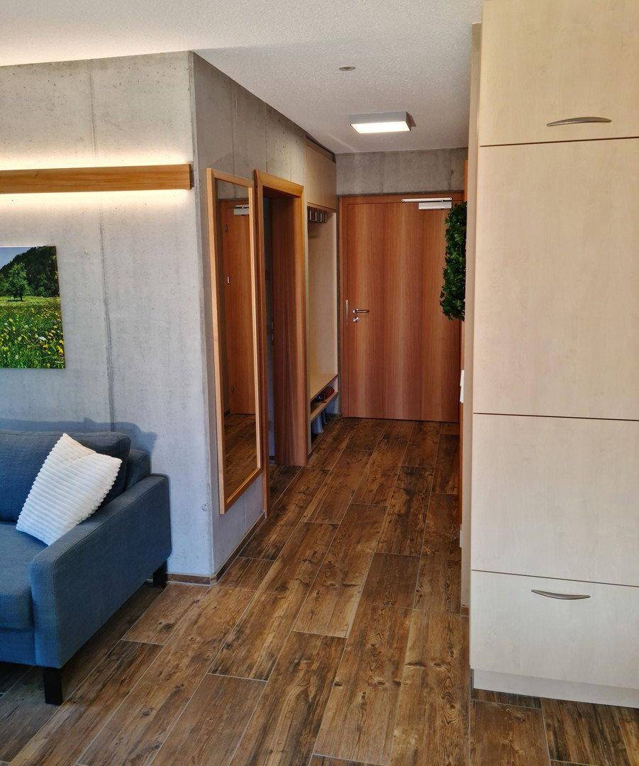Flur mit Holzboden, Garderobe und Spiegel, der zum offenen Wohnbereich führt.