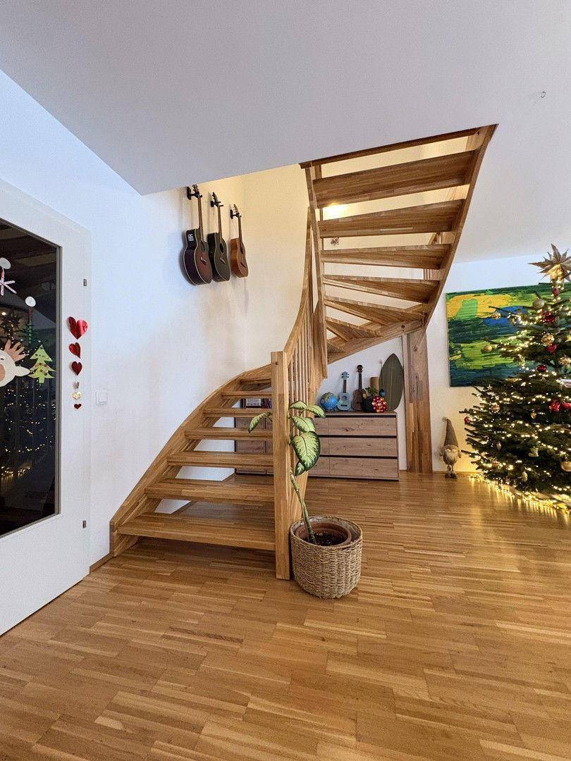 Elegante Holztreppe im Wohnbereich, die in die obere Etage führt, mit Musikinstrumenten an der Wand.
