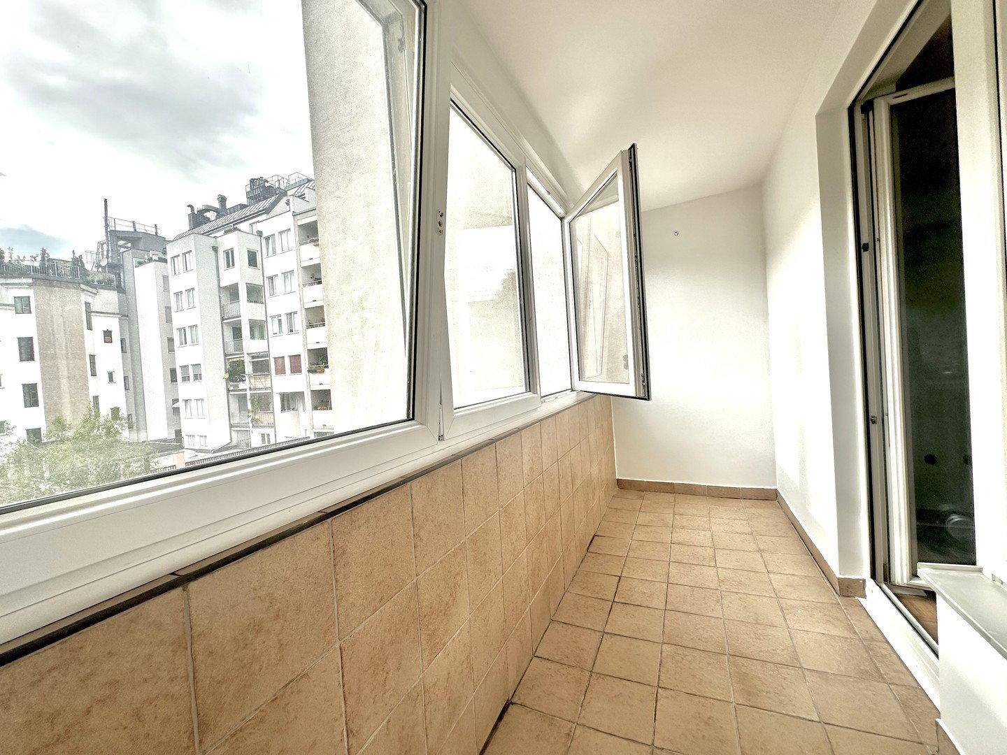 Heller Balkon mit Fliesenboden und weitem Blick über die städtische Umgebung.