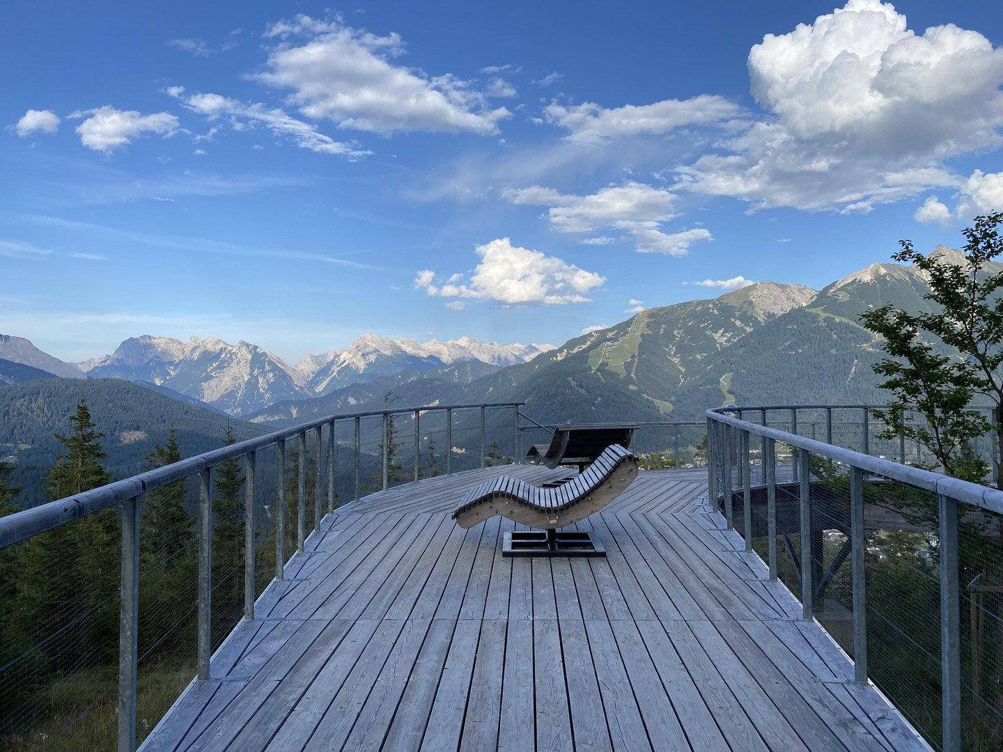 Aussichtsplattform mit Holzdeck und atemberaubendem Panoramablick auf die Berge.
