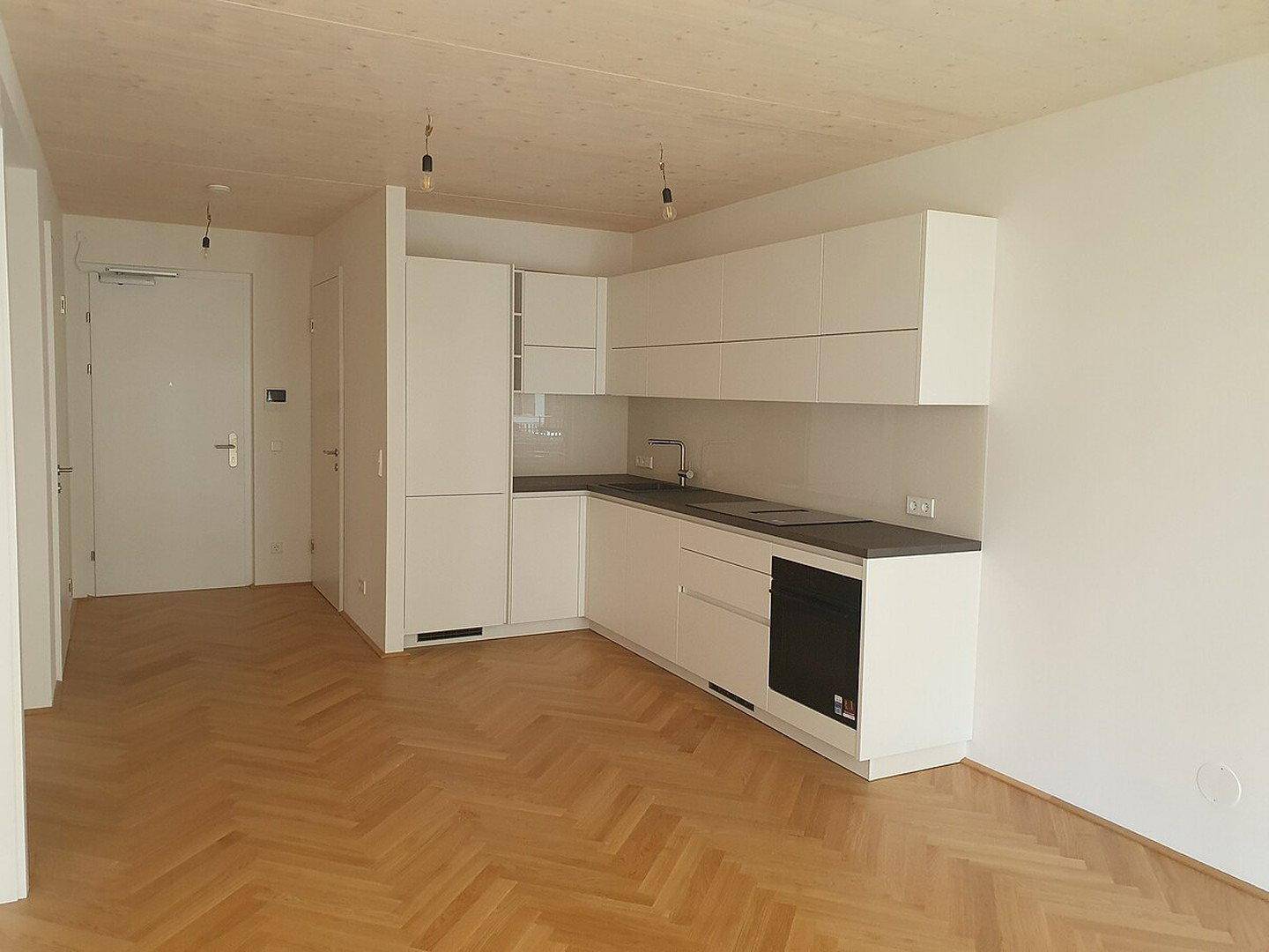 Geräumige, moderne Küche mit weißen Schränken, dunkler Arbeitsplatte und offenem Grundriss.