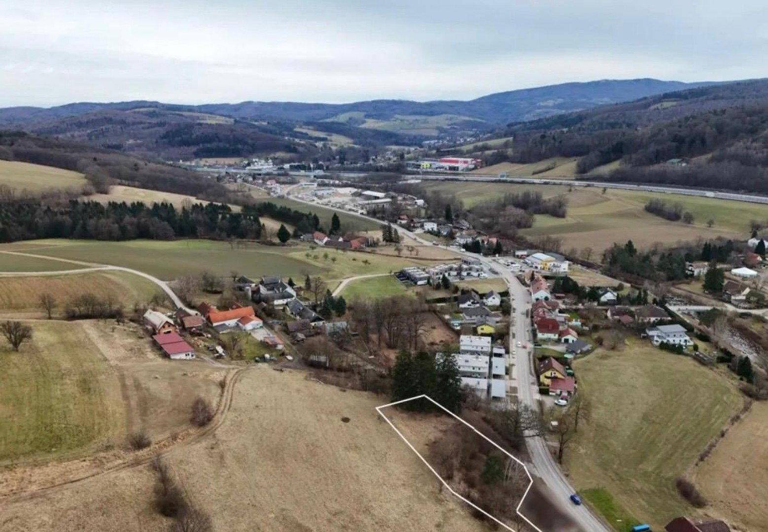 Luftaufnahme eines Grundstücks in ländlicher Umgebung mit umliegenden Feldern und Hügeln.