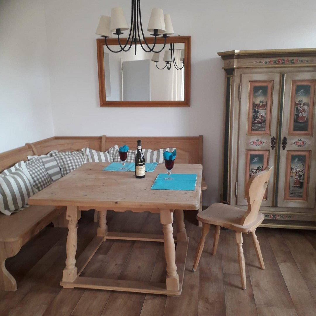 Gemütlicher Essbereich mit traditioneller Eckbank, Holztisch und einem kunstvoll bemalten Schrank.