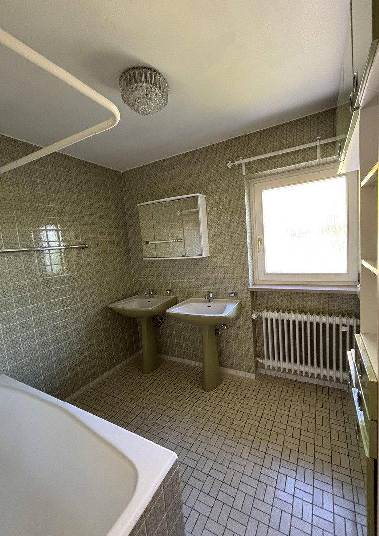 Geräumiges Badezimmer mit Badewanne, zwei Waschbecken und Fenster.
