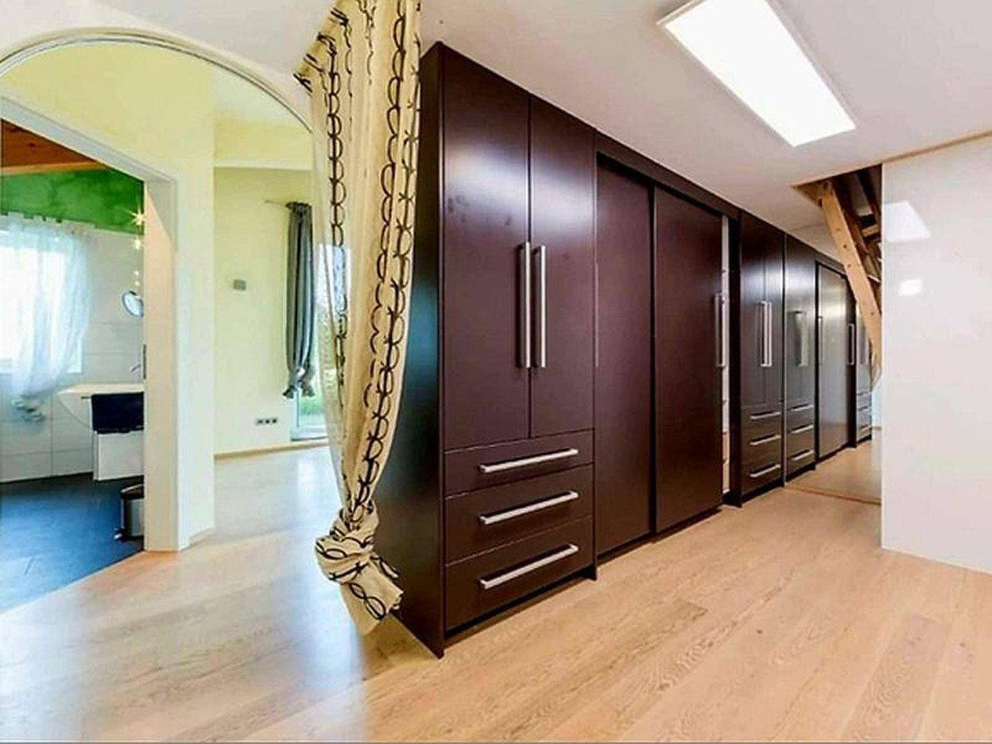 Geräumiger Flur mit Einbauschränken und Holzboden, der zu weiteren Räumen führt.