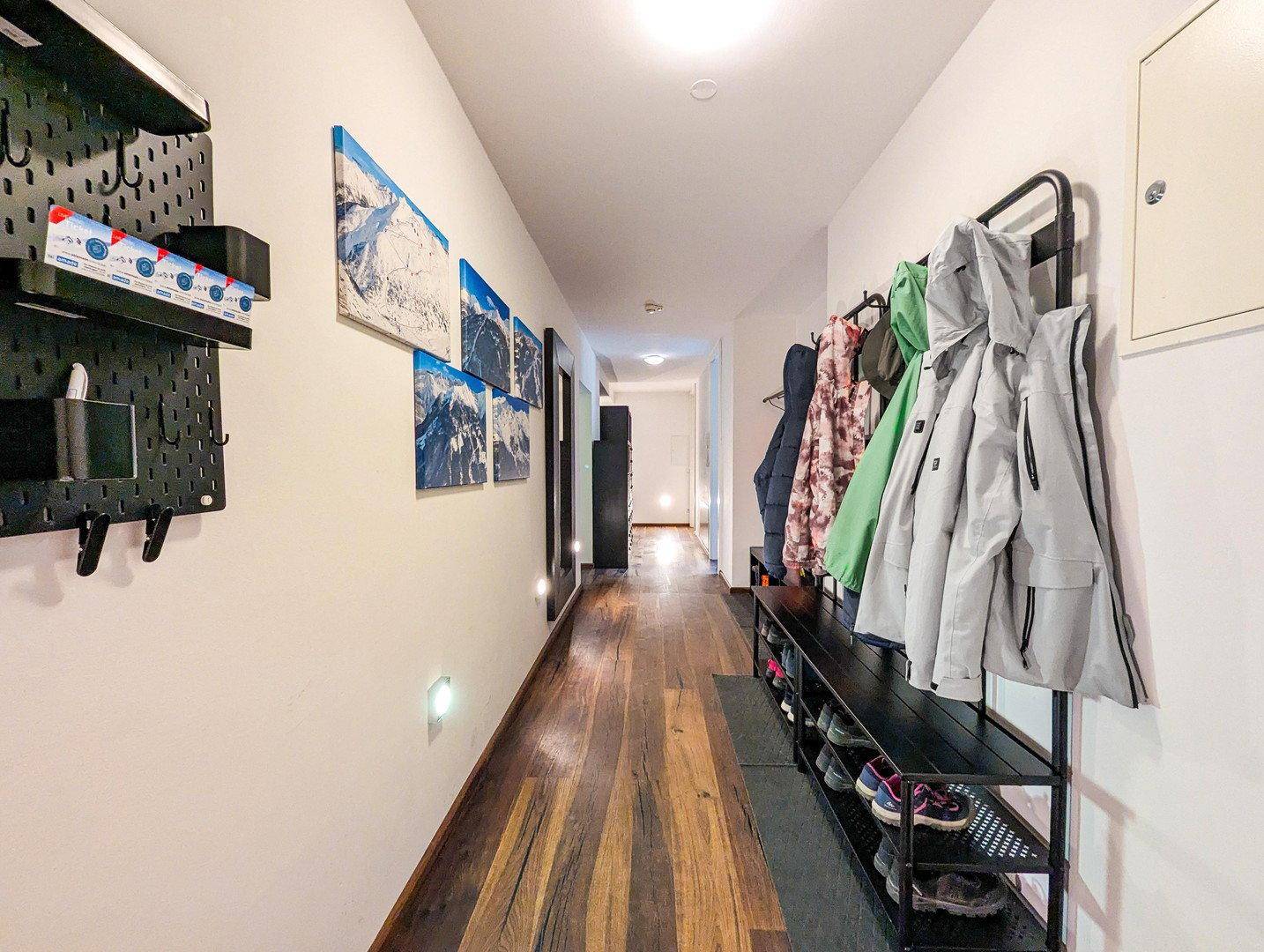 Langer Flur mit Garderobe, Schuhregal und Holzboden, führt zu weiteren Räumen.