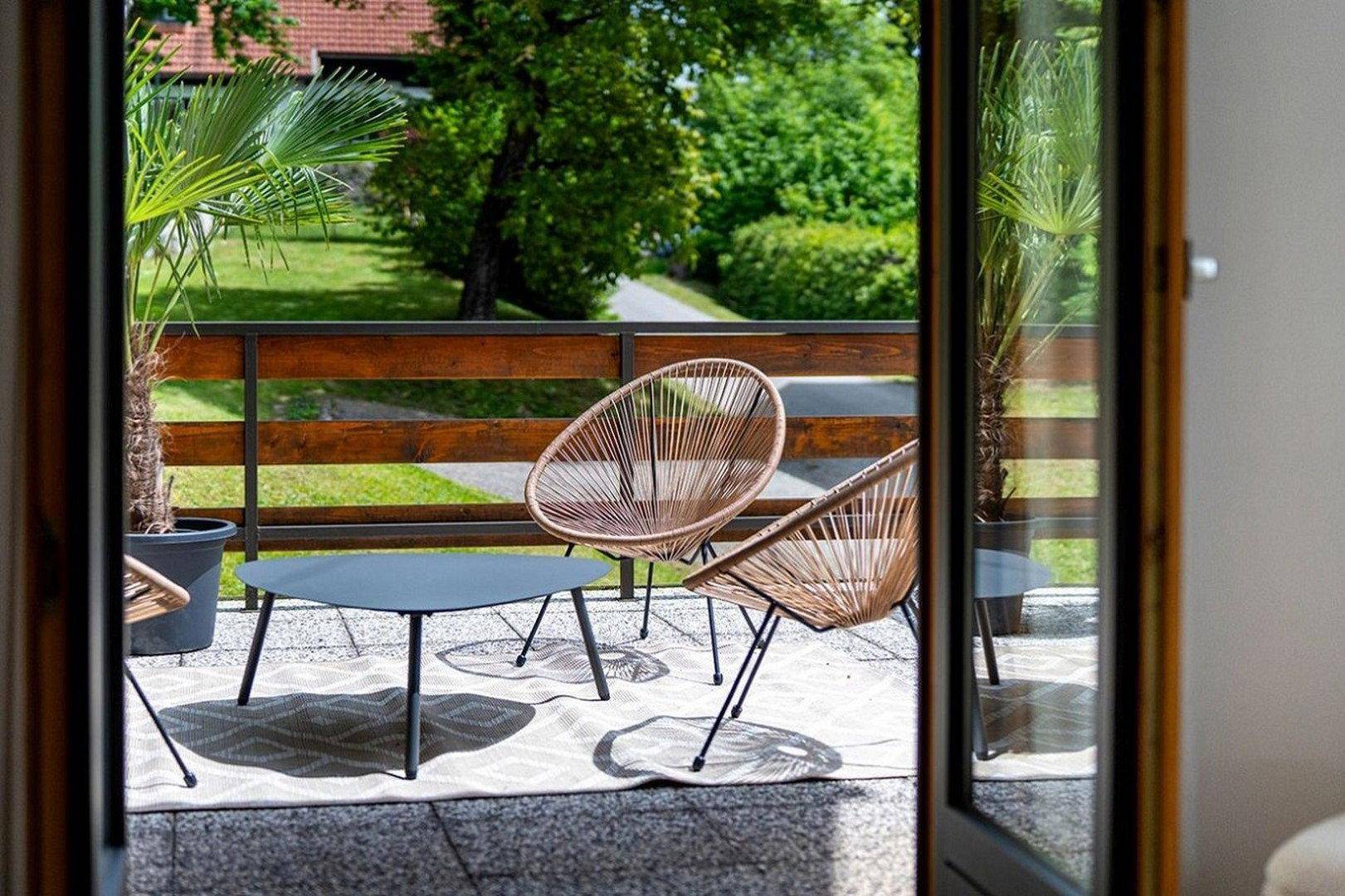 Gemütlicher Balkon mit modernen Sitzgelegenheiten und Blick ins Grüne.