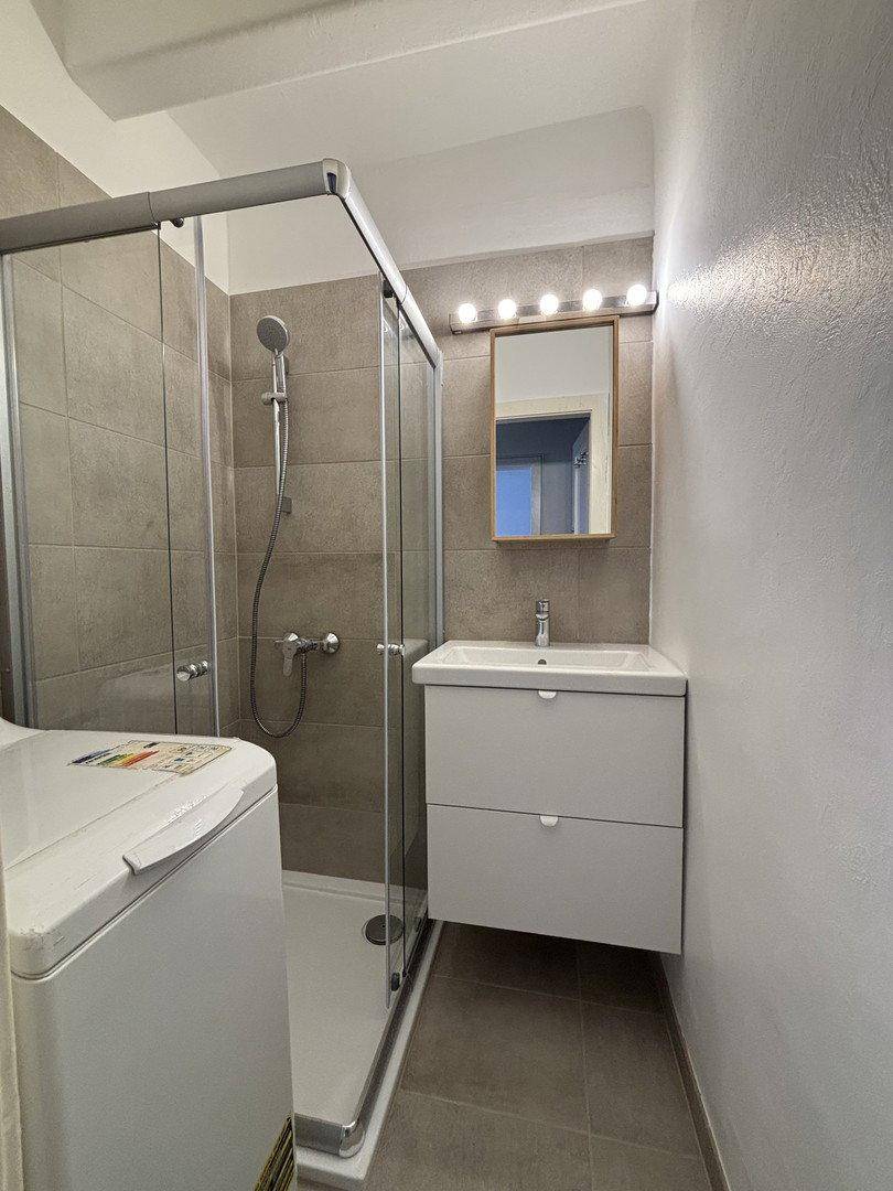 Modernes Badezimmer mit Duschkabine, Waschbeckenunterschrank und einer Waschmaschine.