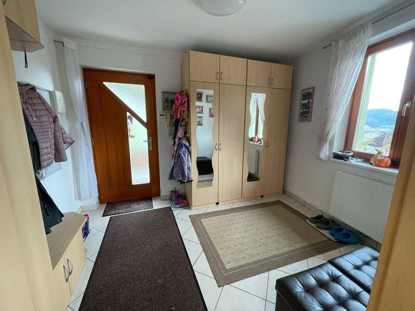 Eingangsbereich mit Garderobe, Spiegelschrank und Fenster mit Blick nach draußen.