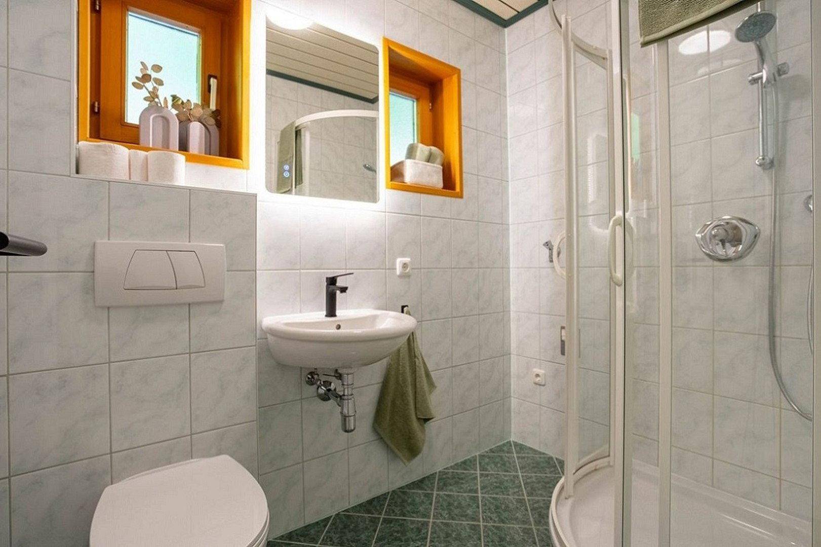 Modernes Badezimmer mit Dusche, WC, Waschbecken und Fenster, hell gefliest.