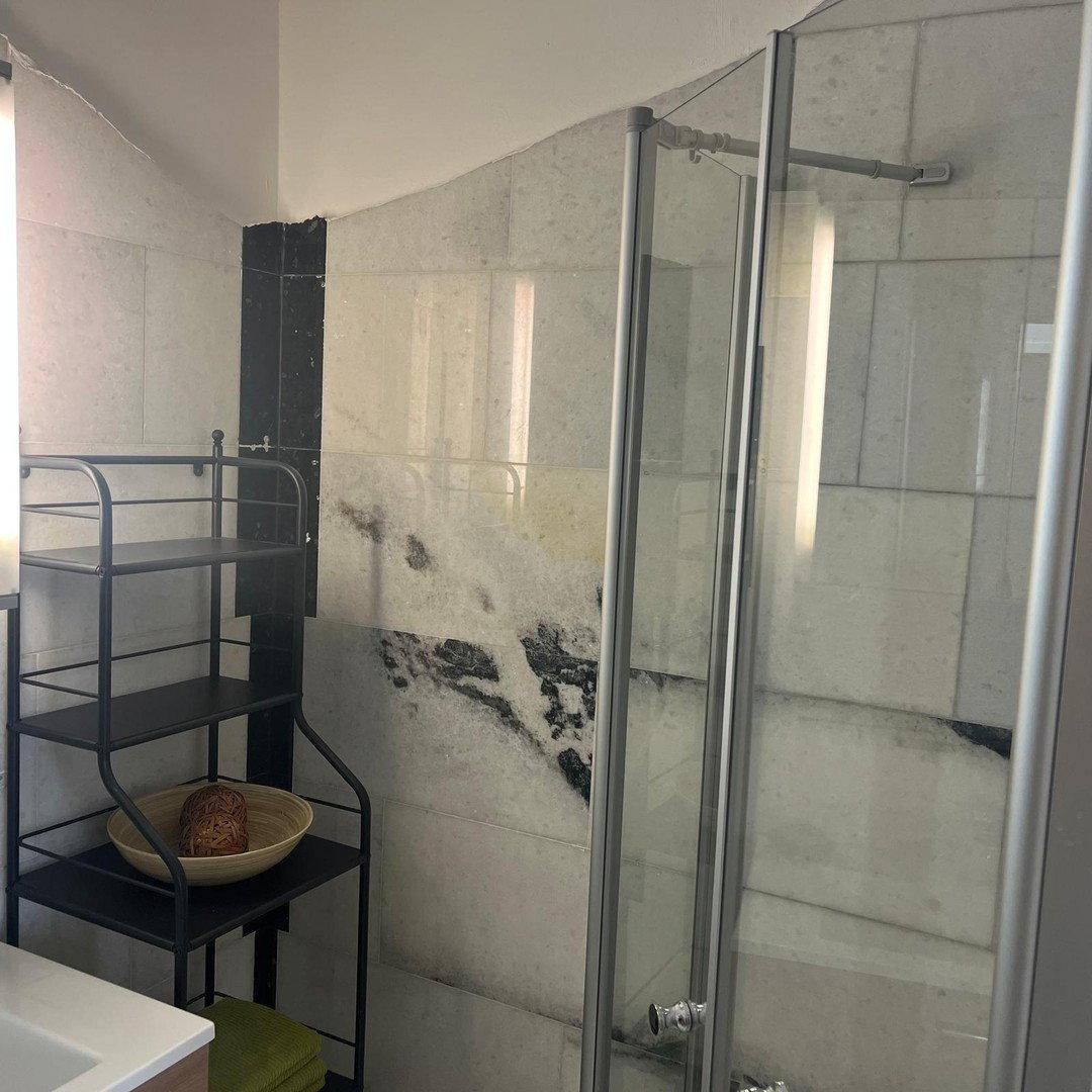 Modernes Badezimmer mit Duschkabine, eleganten Marmorfliesen und praktischem Regal.